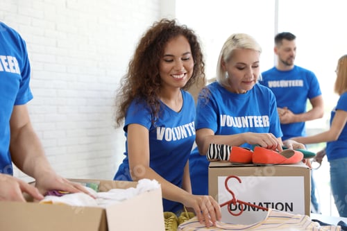 Preview: Team of volunteers collecting donations in boxes indoors