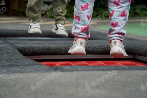 Preview: Close up of children feet jumping together on trampoline on the park floor