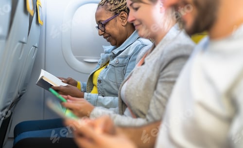 Preview: Passengers reading book and using mobile smartphones during airplane trip