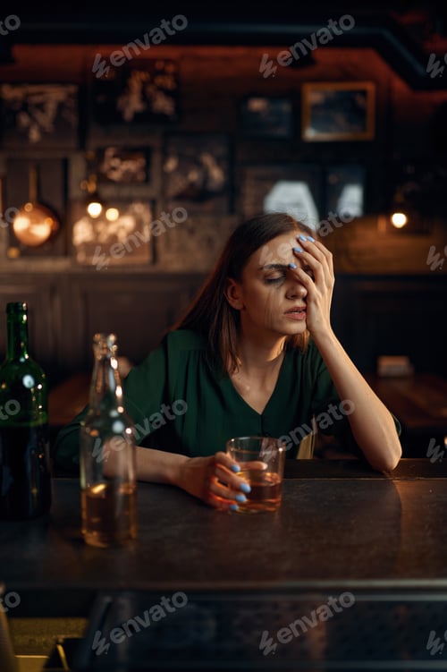 Preview: Stressed woman drinks alcohol beverage in bar