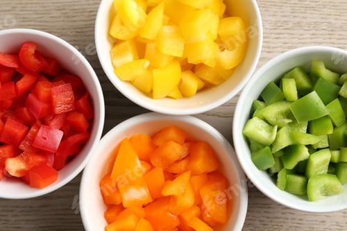 Preview: Pieces of fresh colorful bell peppers in bowls on wooden table, flat lay