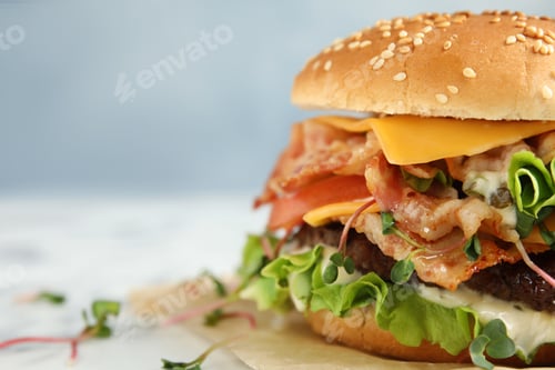 Preview: Tasty burger with bacon on table, closeup. Space for text