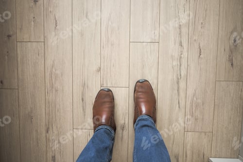 Preview: Feet in brown shoes on wooden floor with blue jeans