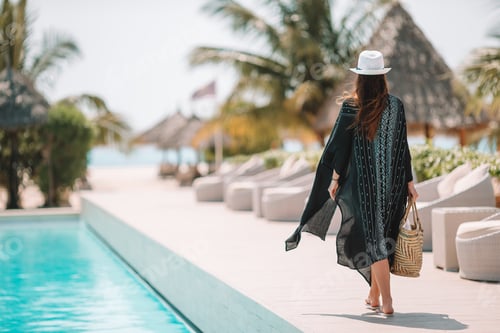 Preview: Woman relaxing by the pool in a luxury hotel resort enjoying perfect beach holiday vacation