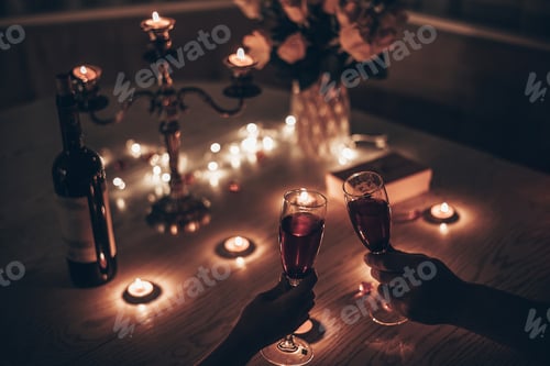 Preview: Couple with glasses of wine having romantic candlelight dinner at table at home,