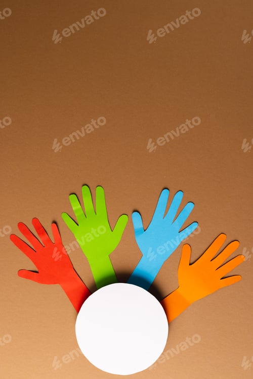Preview: Paper cut out of multi coloured hands and white circle with copy space on brown background
