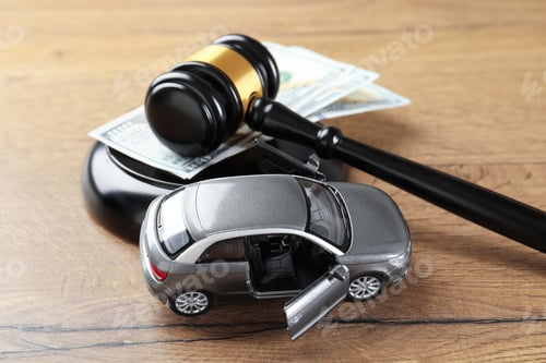 Preview: Auto accident law. Judge's gavel, toy car and dollar banknotes on wooden table, closeup