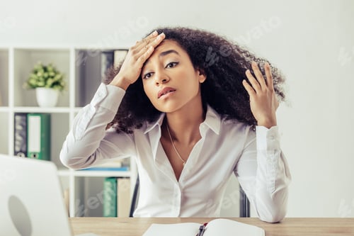 Preview: pretty african american businesswoman holding hand on head while suffering from heat in office