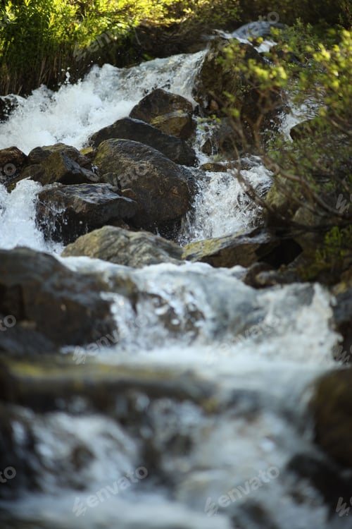 Preview: Idyllic scene of nature featuring a tranquil waterfall cascading over a cluster of large grey stones