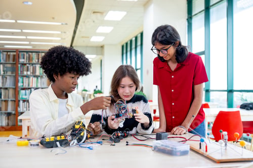 Preview: Multiracial teen girl explain about how to assemble the robot and discuss with friends in library.