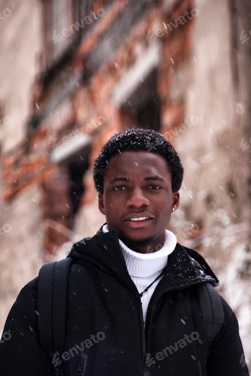 Preview: Young Man Smiles Through Snow in Winter Near Old Building