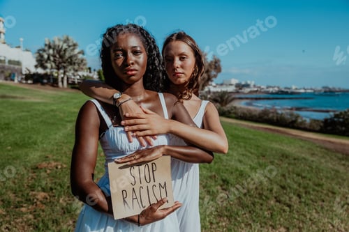 Preview: Two women with serious gaze are holding a sign that says "Stop Racism"