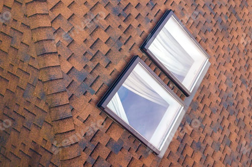 Preview: Close-up of new small attic plastic windows installed in brown shingled house roof.