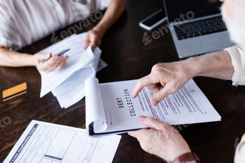 Preview: Cropped view of senior man pointing at paper with debt collection lettering near gadgets and wife at