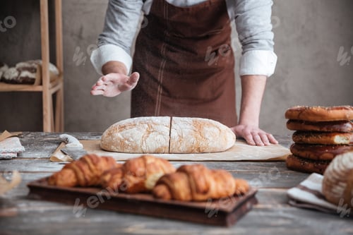 Preview: Young man baker cut the bread.