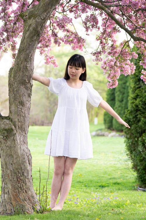 Preview: Portrait of a girl teen smiling under pink flower tree