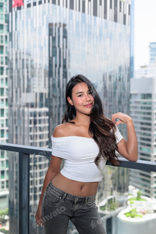 Preview: Young Asian woman posing on a high-rise balcony with modern skyscrapers in Kuala Lumpur, Malaysia