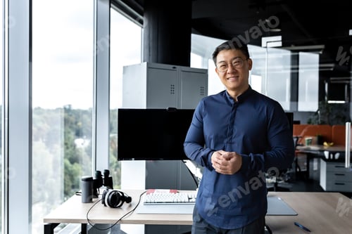 Preview: Programmer in glasses and shirt smiling and looking at camera, Asian man working inside modern