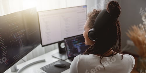 Preview: Back view of young professional woman programmer working from home sitting at desk