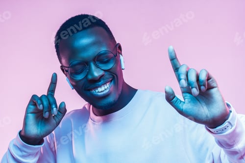 Preview: Portrait of happy young african man listening to music with wireless earphones