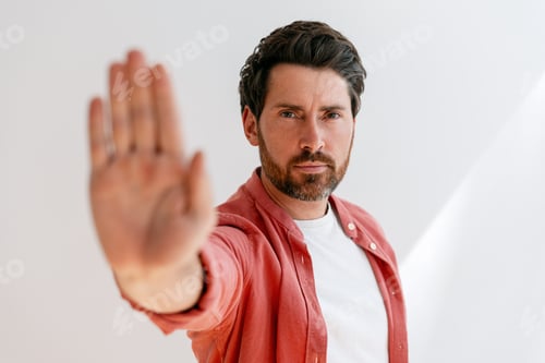 Preview: Serious man showing stop gesture with hand in front of white background