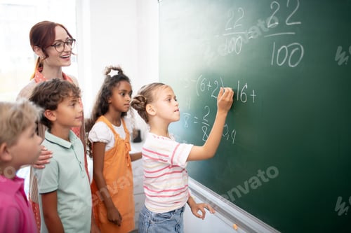 Preview: Smart girl writing down numbers on blackboard during math class