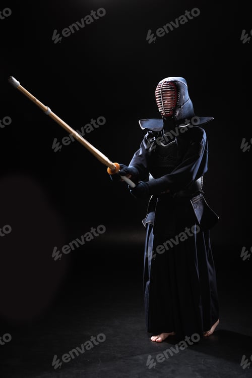 Preview: Full length view of kendo fighter in armor practicing with bamboo sword on black