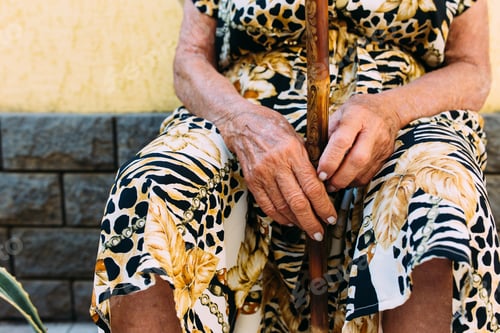 Preview: The wrinkled hands of a old woman are holding an old lady's wooden hook.