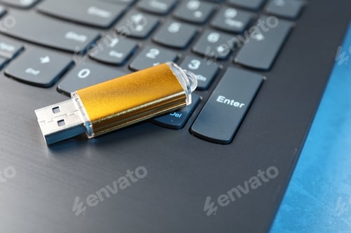 Preview: Usb flash drive and laptop on blue table, closeup
