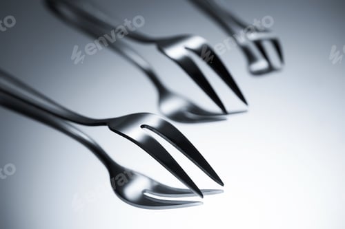 Preview: close-up view of forks with two tines reflected on grey