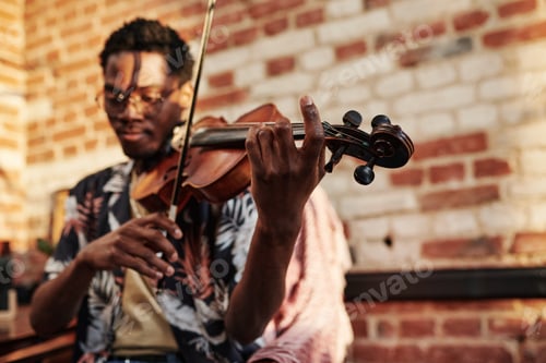 Preview: Hands of young black man holding fiddlestick and touching strings of violin