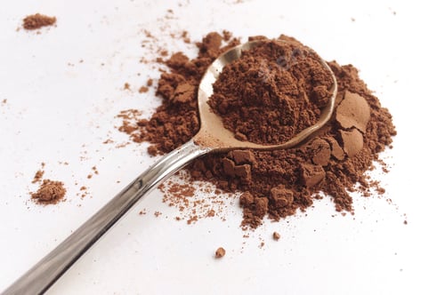 Preview: Spoon with dark cocoa powder on white kitchen counter