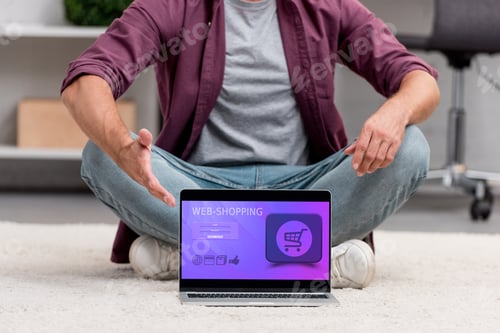 Preview: cropped view of man pointing at laptop with online shopping illustration