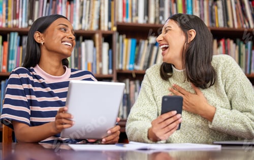 Preview: Make each day a little better than before. Shot of two females using their devices in a library.