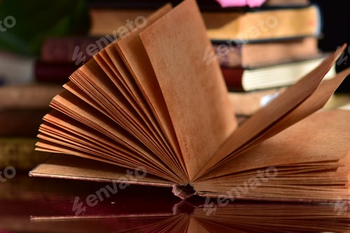 Preview: An unfolded old notebook with books on a wooden desk