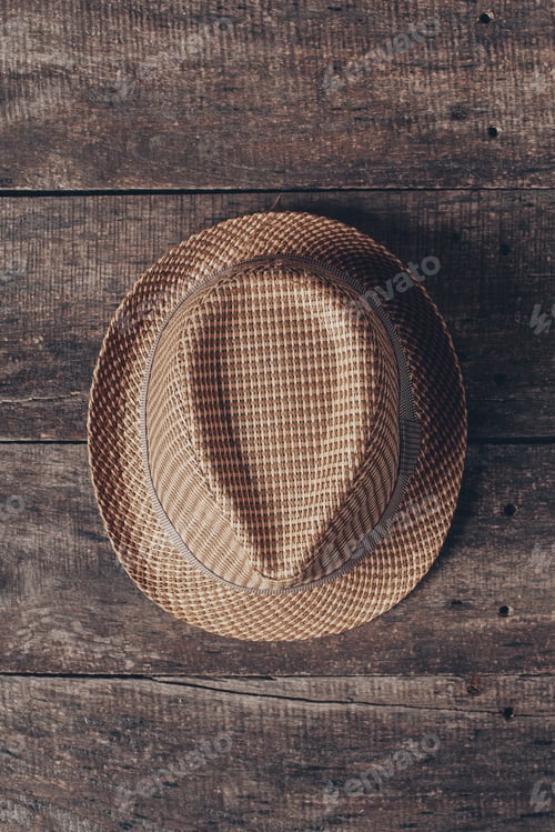 Preview: Stylish woven hat resting on rustic wooden surface, showcasing intricate details and texture during