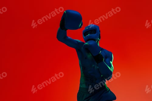 Preview: Sporty man wearing head guard and boxing gloves practicing for fight on studio background