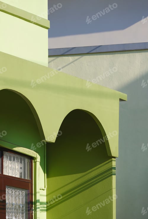 Preview: Sunlight and shadow on surface of arch awning with window on balcony of green vintage house