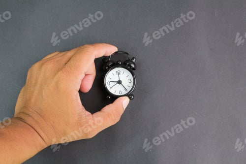 Preview: hand holding a black bell clock. the concept of waking up