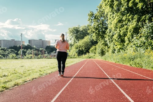 Preview: Training at the stadium, outdoors. Young plus size woman walking outside on sunny summer day