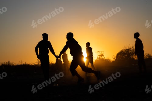 Preview: Silhouette shot of Boys Playing soccer at sunset time