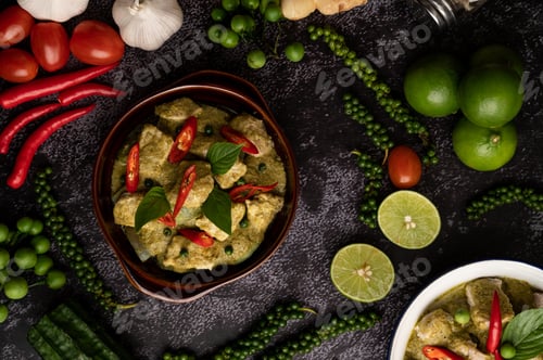 Preview: Pork green curry in a brown bowl with spices on a black cement background