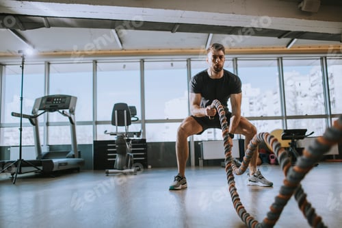 Preview: Young man practicing with battle ropes in the gym