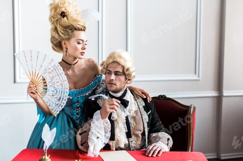 Preview: young victorian woman holding fan and standing near pompous man holding feather near paper