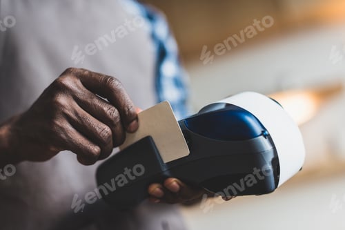 Preview: cropped view of african american waiter making transaction with credit card in cafe