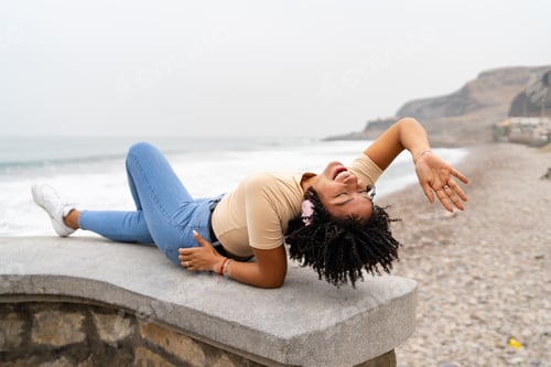 Preview: Carefree black woman listening music with headphones by the sea
