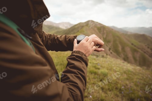 Preview: Hiker on high altitude mountain top checking the altitude on the sportswatch