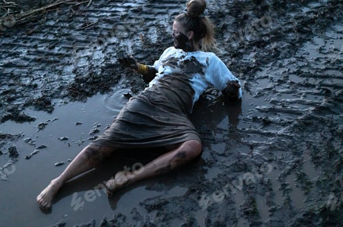 Preview: A happy authentic woman stuck in a mud puddle in a field