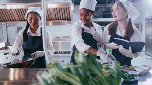 Preview: Group of schoolgirls having fun learning to cook. Female students in a cooking class.