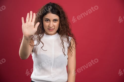 Preview: Woman with curly hair doing stop sing on red background